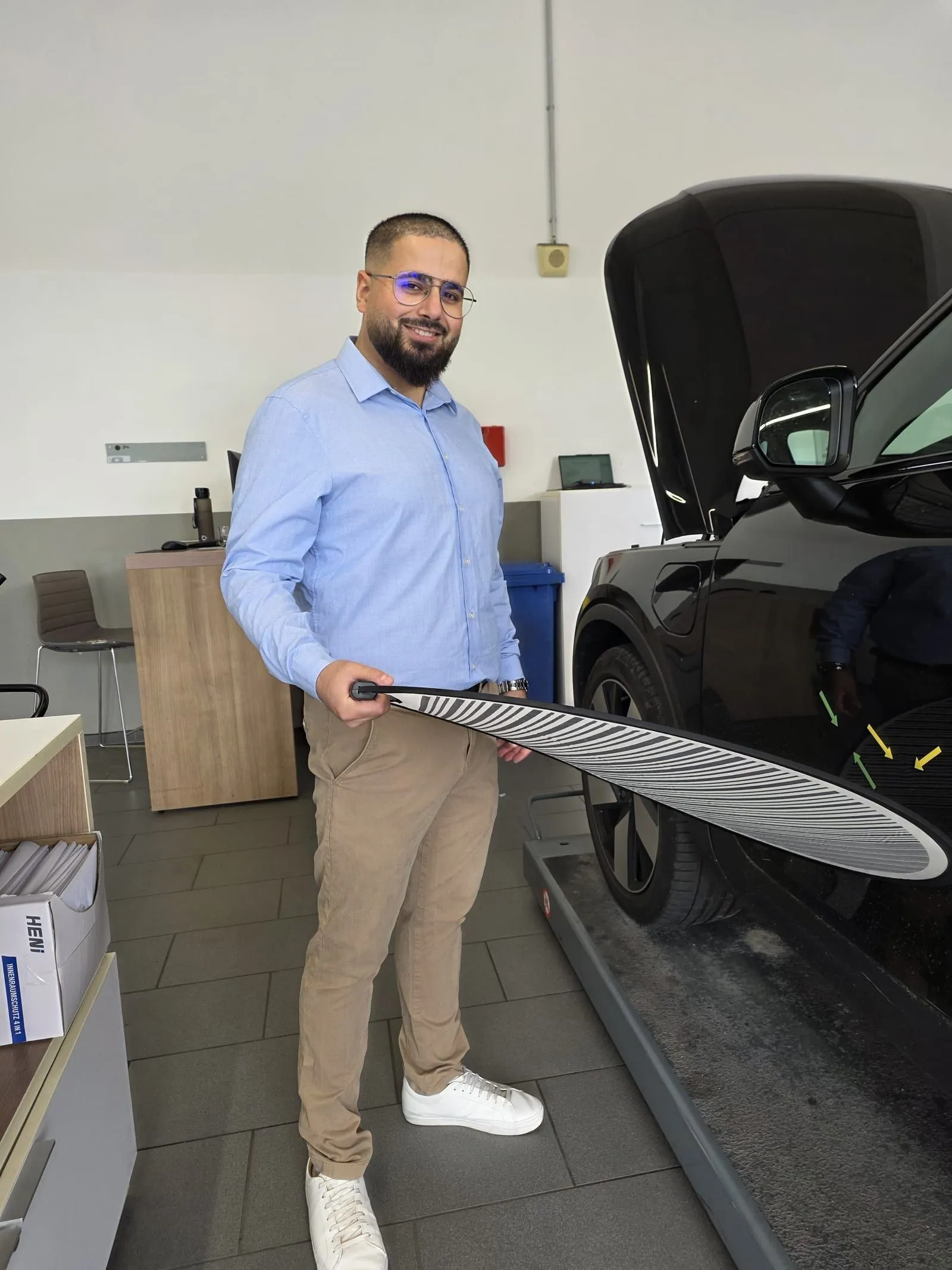 Muhammed Erdogdu mit einer Reflexionstafel, mit der sich Dellen im Lack sichtbar machen lassen.