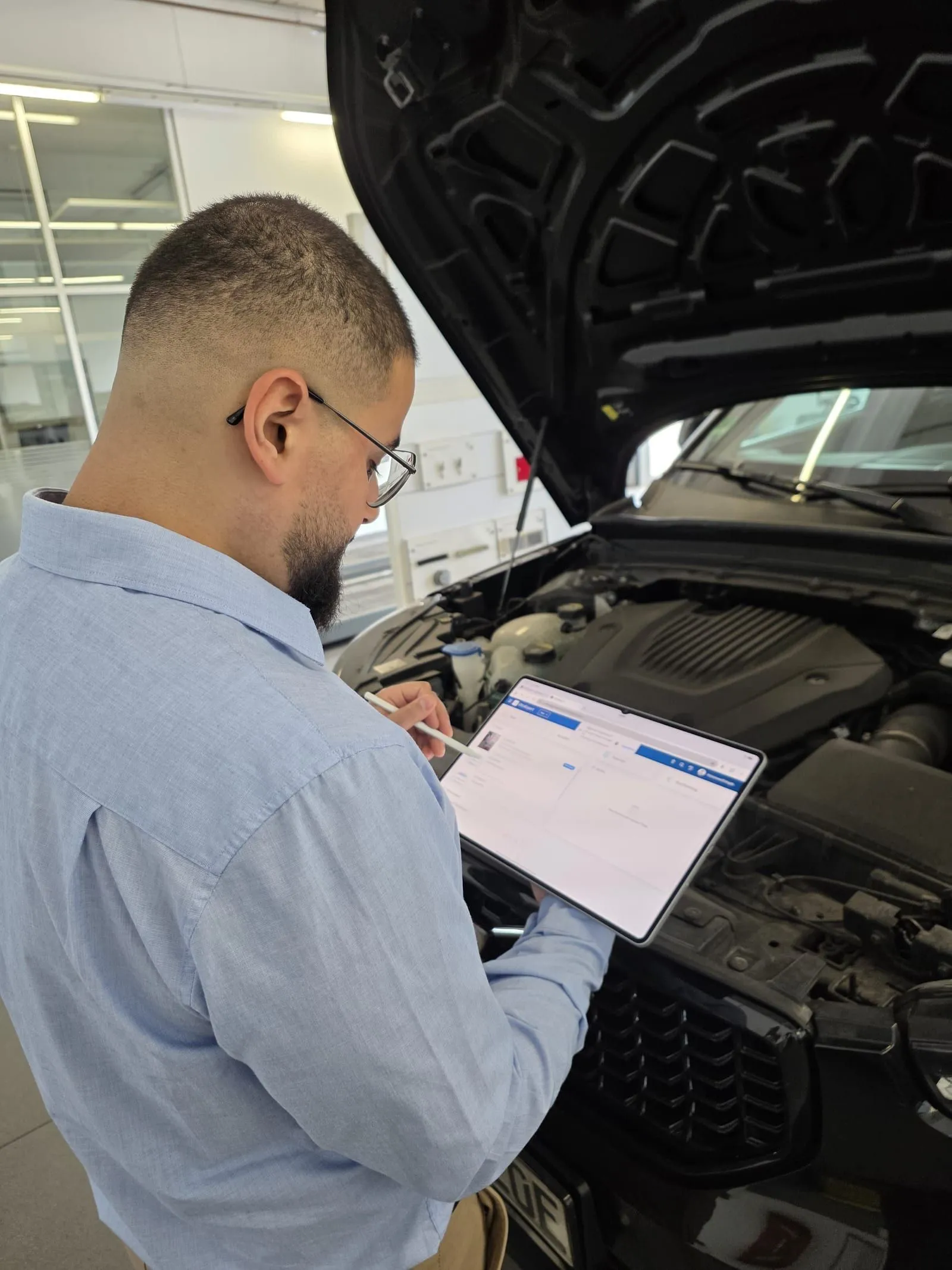 Festhalten des Fahrzeugzustands am Tablet bei geöffneter Motorhaube.